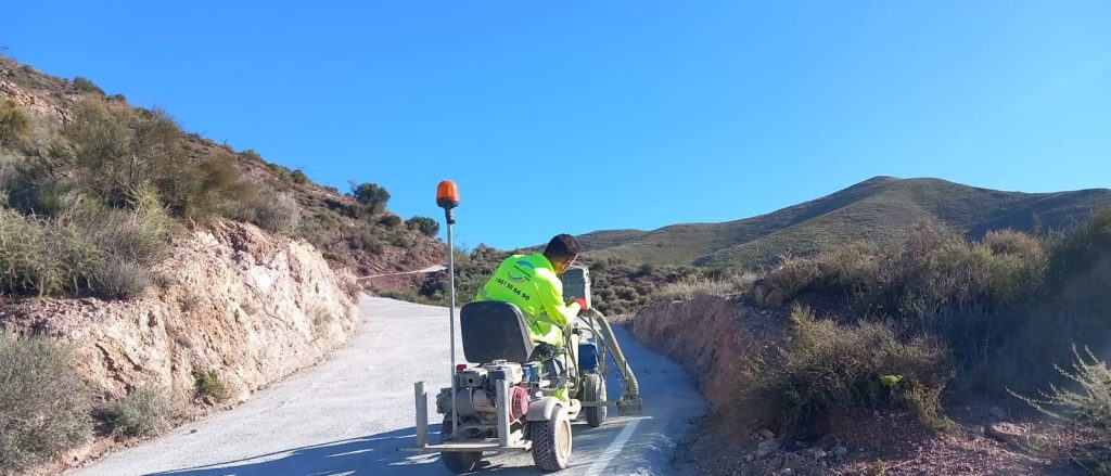 Trabajador pintando línea en una carretera rural